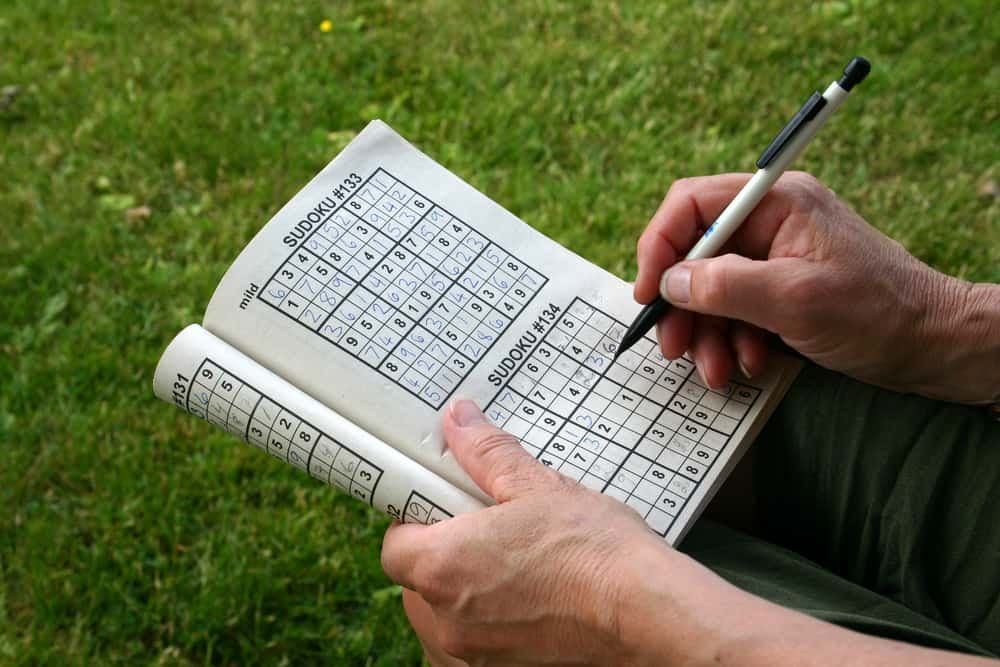 A woman doing a sudoku puzzle with pencil in hand