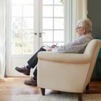 Senior man sitting in an armchair doing sudoku