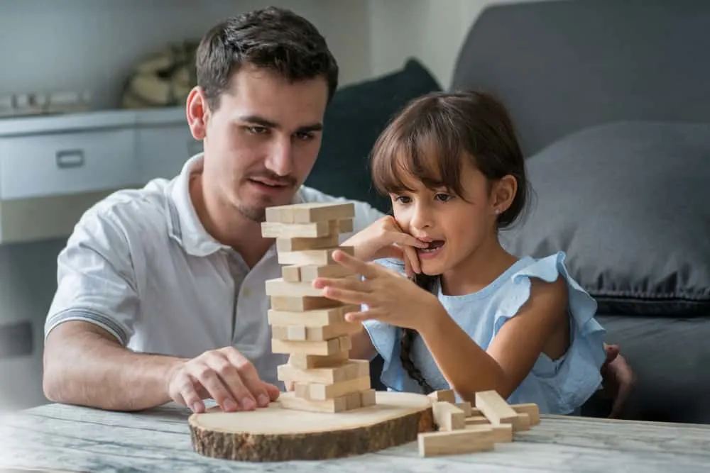 father and his daughter playing with wooden block game (Jenga) at home