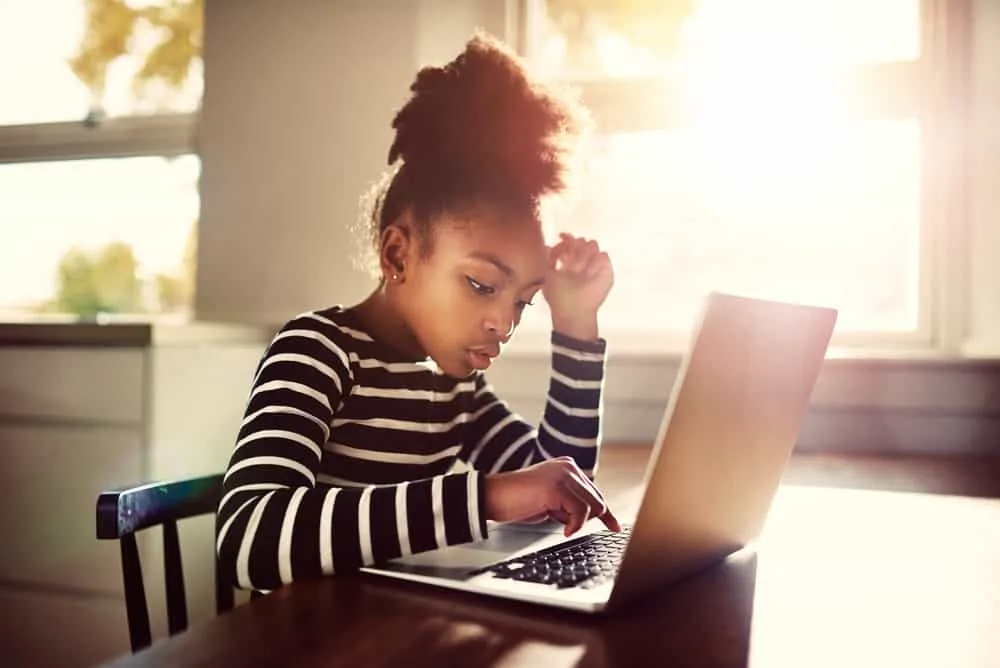 girl sitting at the dining table at home working on her homework from school