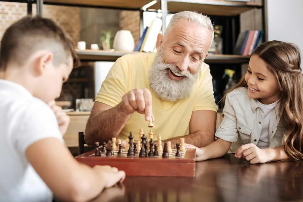 girl watching her brother and grandfather play chess