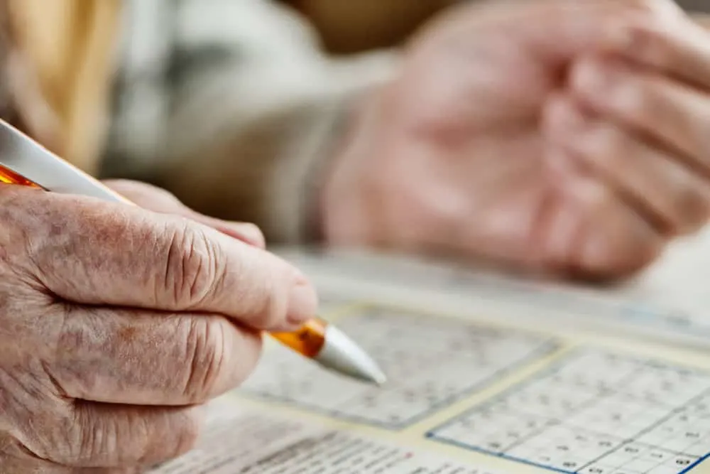 hand of a senior woman, sudoku, crossword