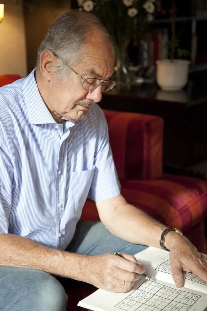 senior man doing sudoko at home