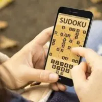 woman with sudoku game application phone at the park