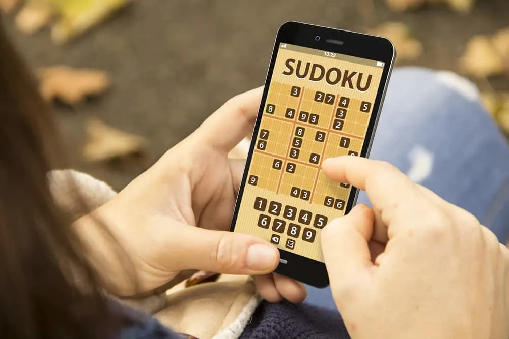 woman with sudoku game application phone at the park