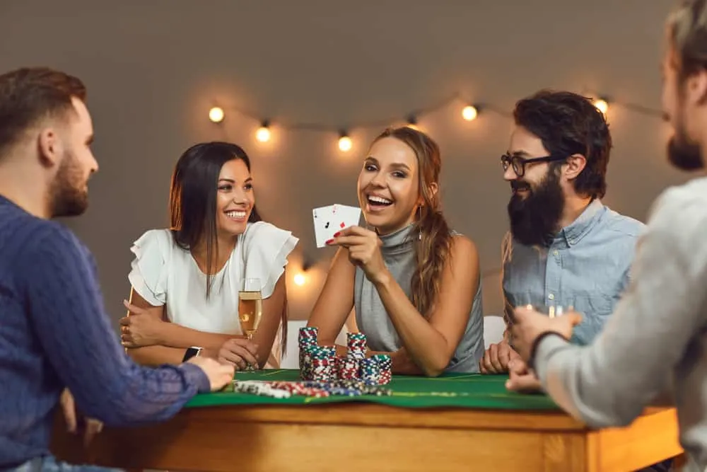 Happy young woman showing two aces while playing poker