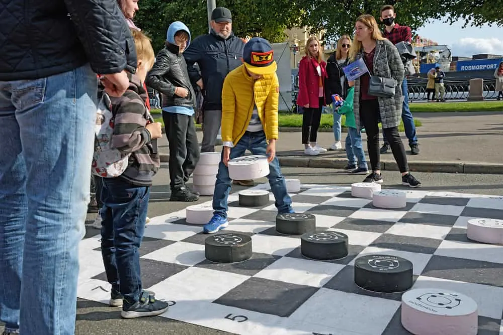 Children play checkers on a large playing field