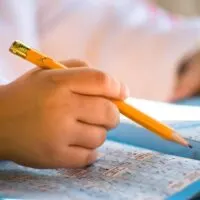 Close up of pencil in child hand over crossword