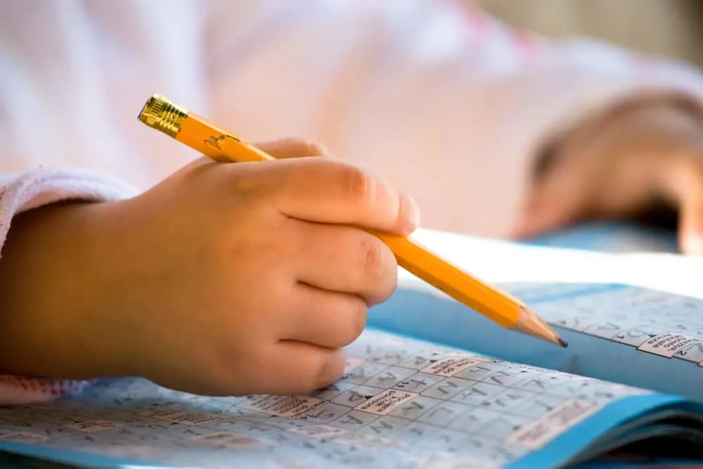 Close up of pencil in child hand over crossword
