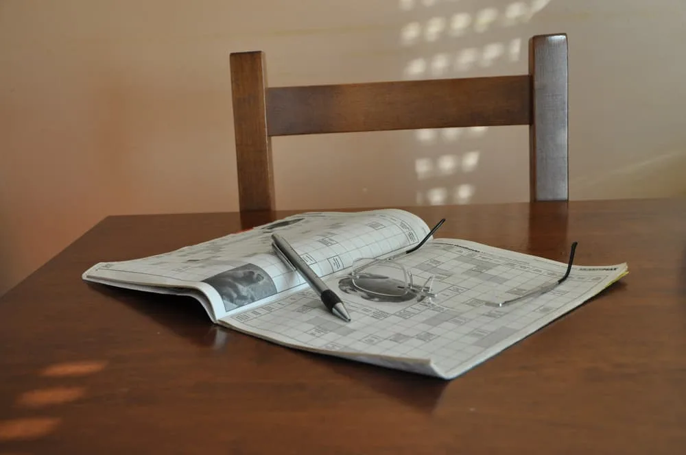 Working on a crossword puzzle. A Newspaper and reading glasses