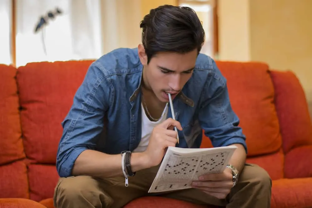 Young man sitting doing a crossword puzzle