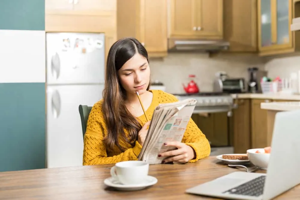 Young woman thinking while solving a crossword puzzle