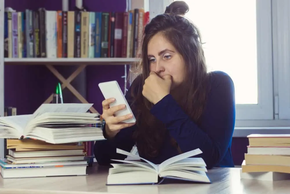 woman distracted with smartphone in the library