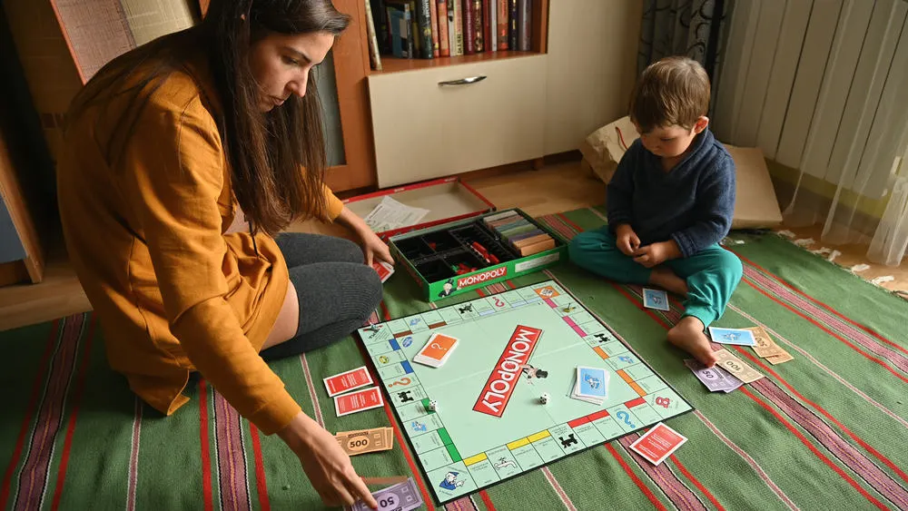 Child with mother playing the board game, monopoly