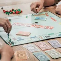 Cropped view of people playing monopoly game at table