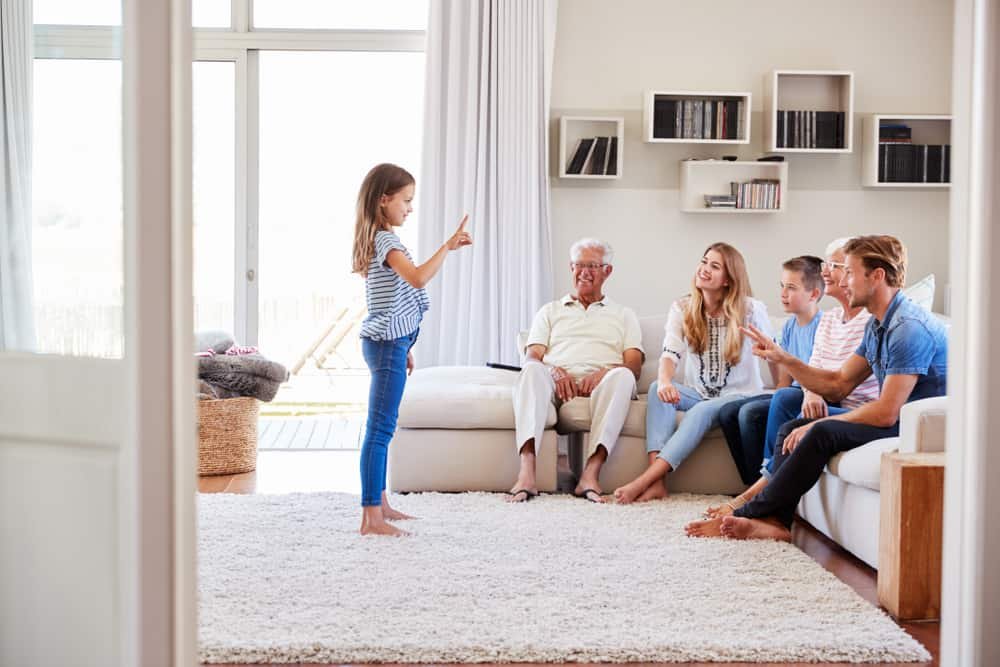 Family Sitting On Sofa At Home Playing Charades, girl acting