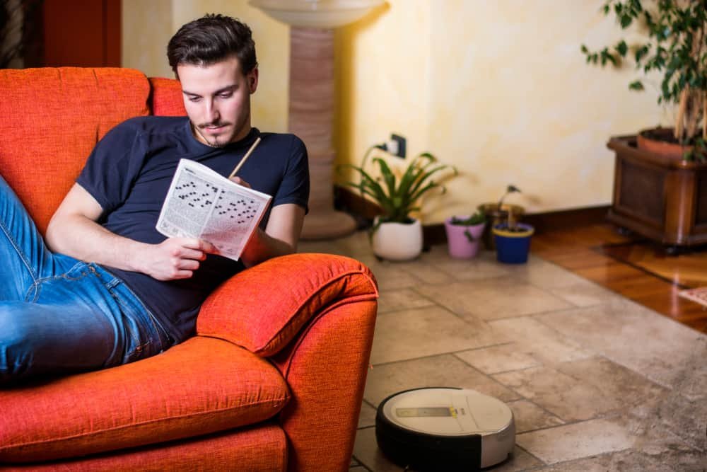 Young man sitting doing a crossword puzzle looking thoughtfully at a magazine