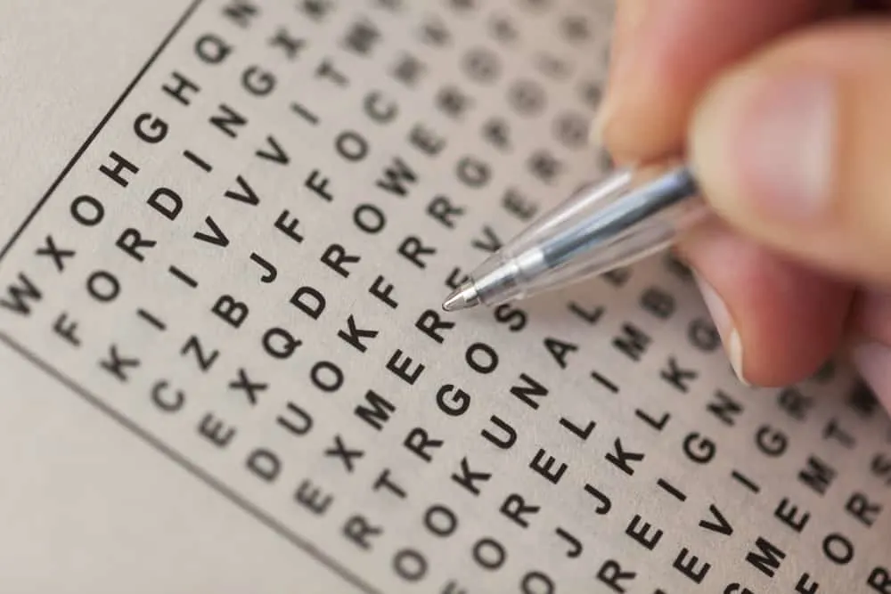 Woman's hand with ballpoint pen and wordsearch puzzle