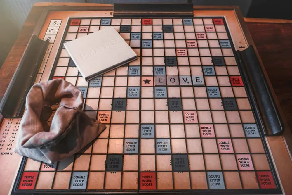 A scrabble letter bag and an instruction book is left on a scrabble board in living room.