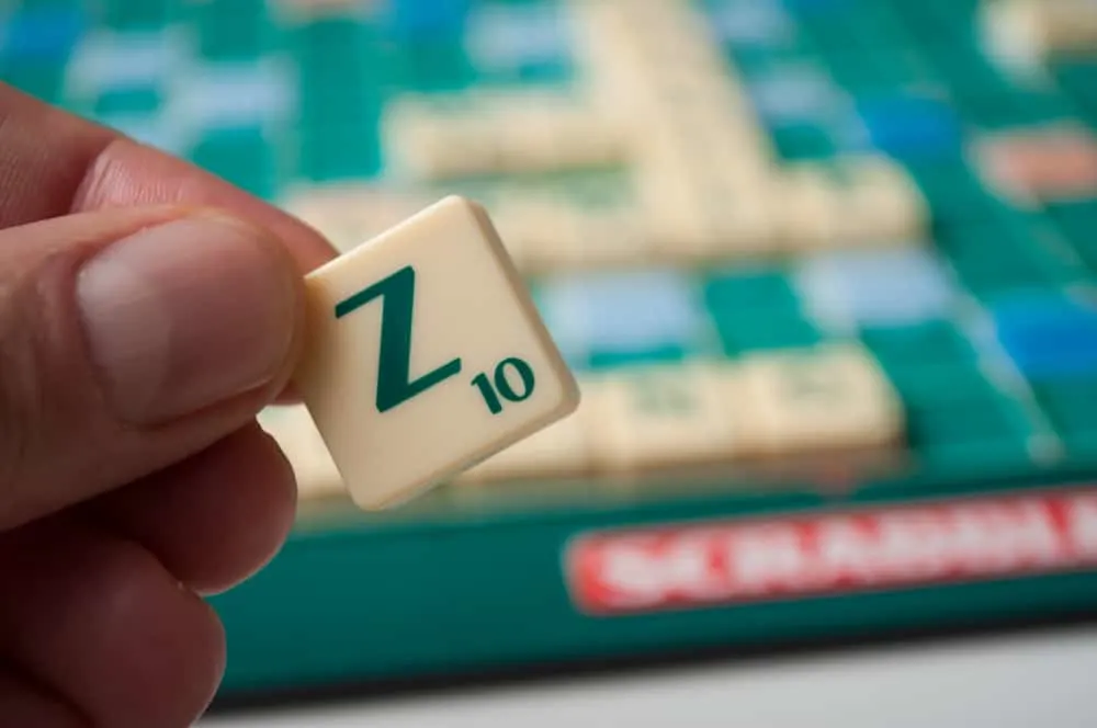 Closeup of plastic letter Z in hand on Scrabble board game