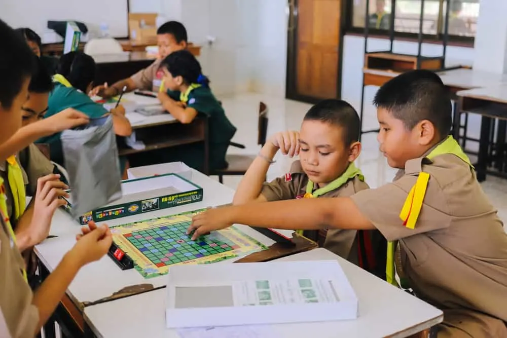 Students in scouting uniform playing Scrabble game in the classroom
