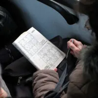 Elderly woman solving sudoku in public