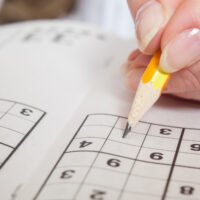 Hand Holding a Pen Playing Sudoku