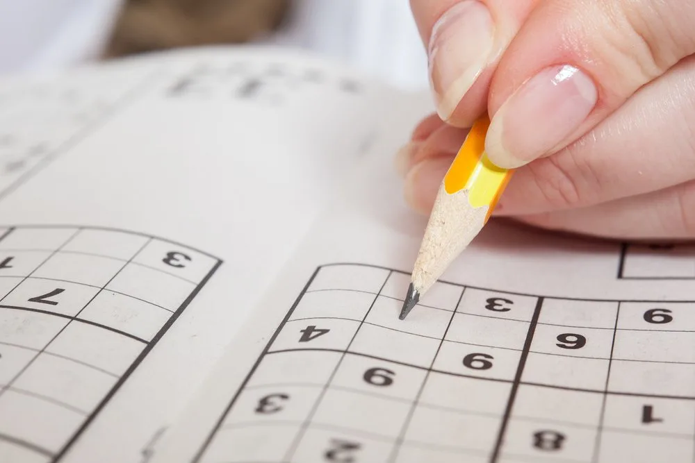 Hand Holding a Pen Playing Sudoku