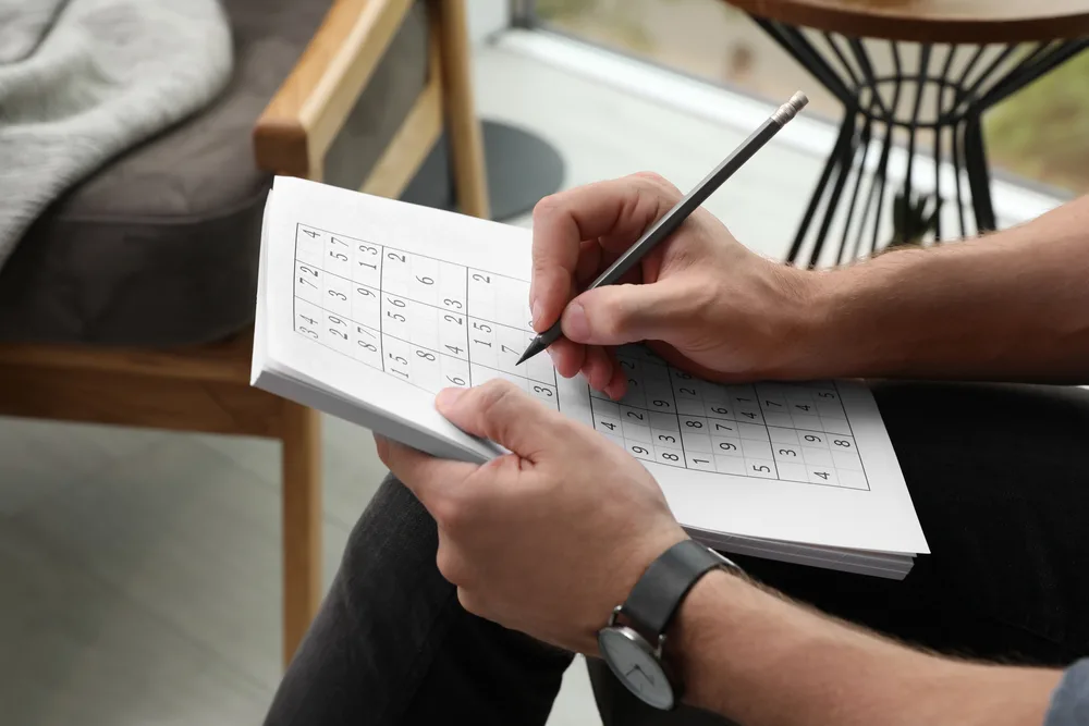 Man solving sudoku puzzle at home