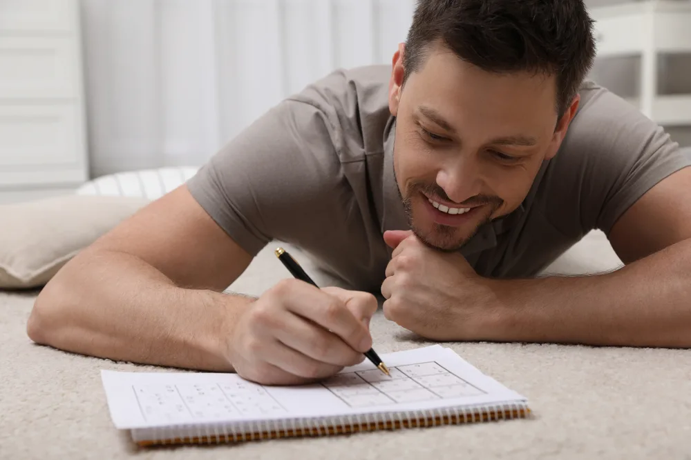 Man solving sudoku puzzle on floor