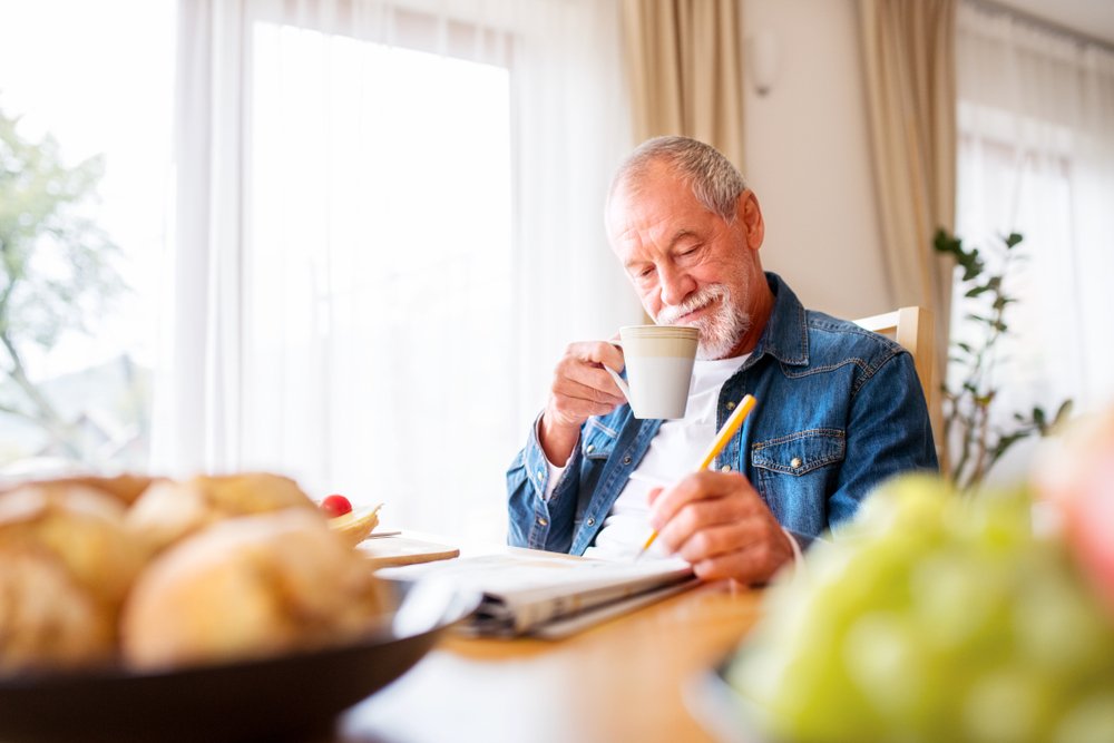  man eating breakfast and doing crosswords 