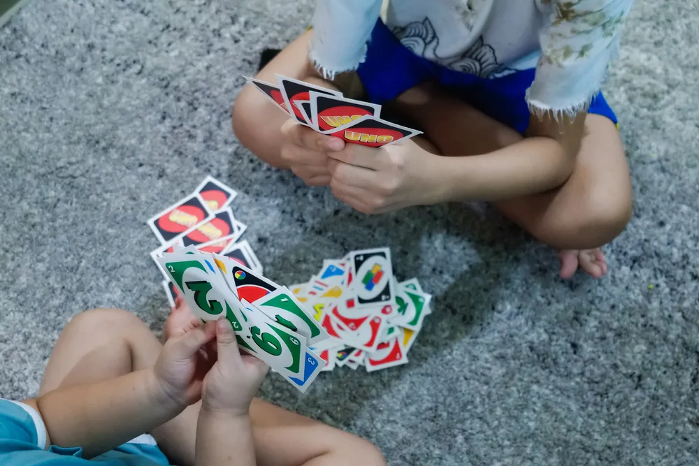 Children are holding and playing UNO card game