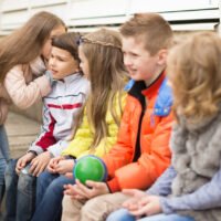 Children on a bench playing Chinese whispers