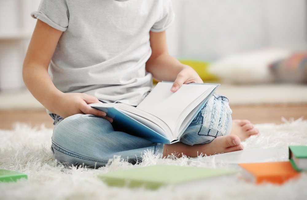 boy sitting on the carpet with book