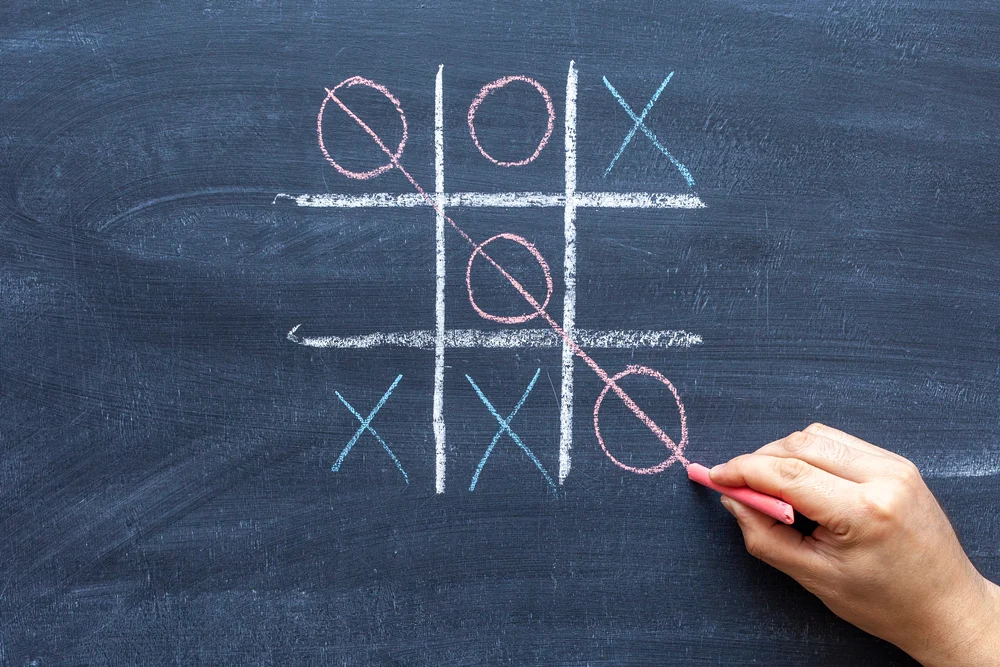 hand drawing a game of tic tac toe with colored crayons