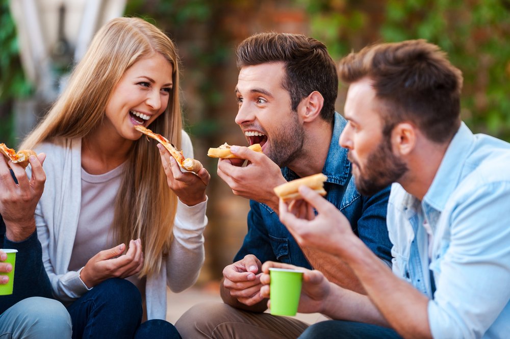 people eating pizza while having fun together