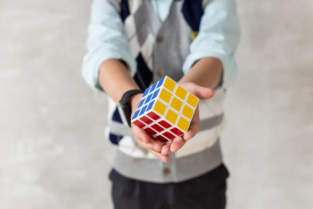 Close-up of Rubik's cube in hands of young boy in casual clothing