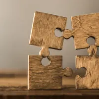 Four brown pieces of puzzle stand on wooden table