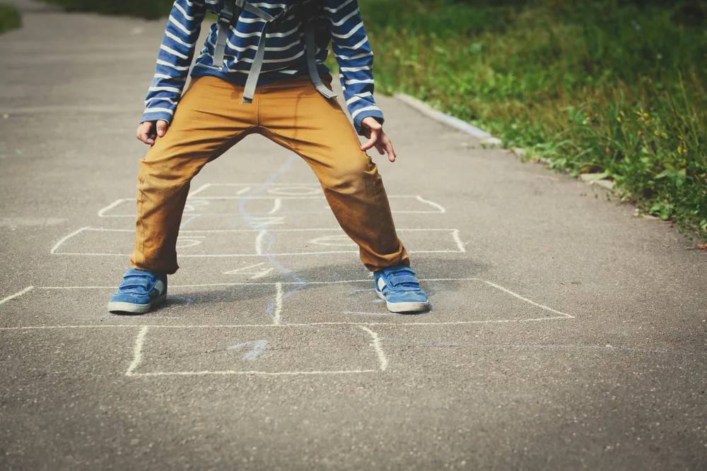 boy playing hopscotch on playground