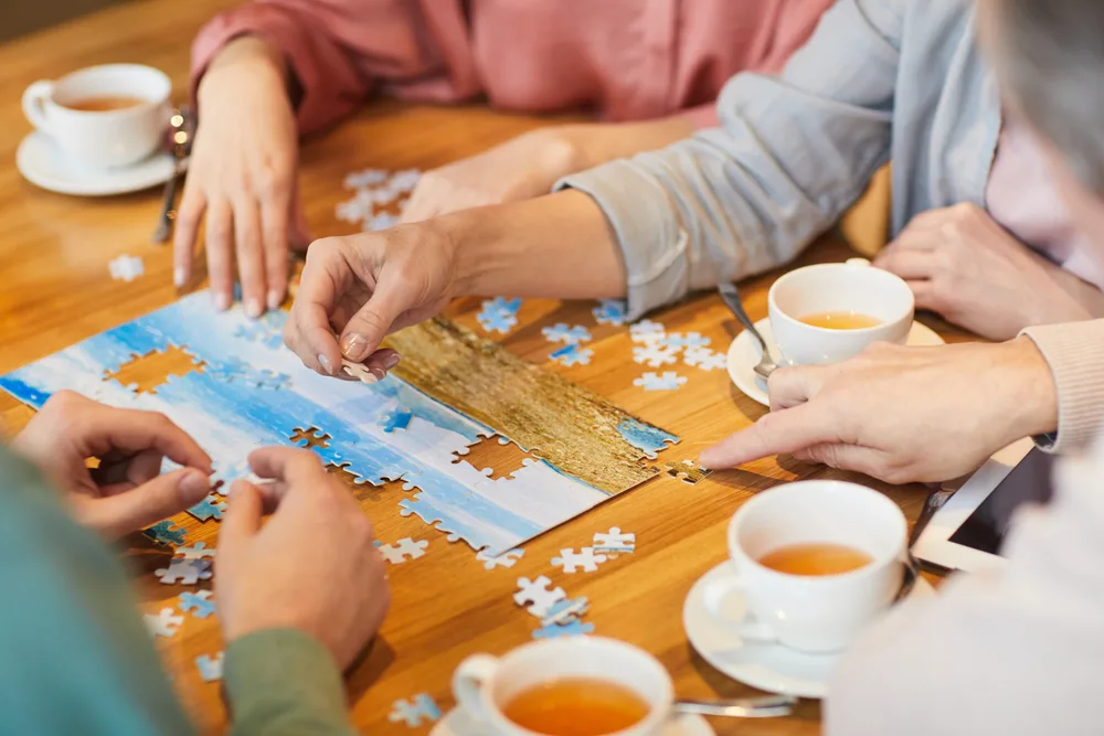 family of four sitting at the table drinking tea and collecting puzzles together