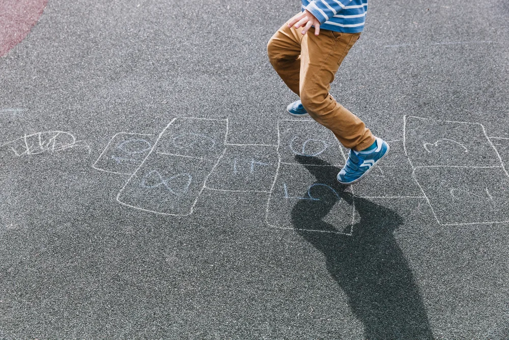 kid playing hopscotch on playground