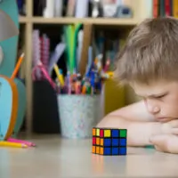 sad kid boy watching at Rubik's cube